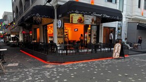 A restaurant with outdoor seating, a menu board, and a sign reading 'Sweet Pine.'