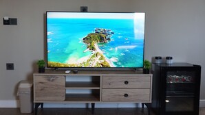 A flat-screen TV mounted on a wooden cabinet with a built-in shelf, a small plant, and a water dispenser.