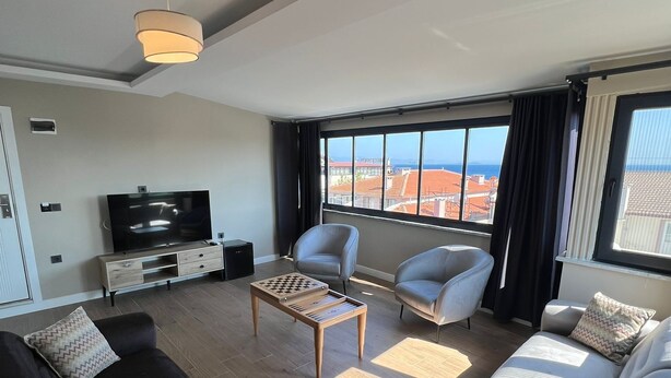 A modern living room with a sofa, armchairs, a coffee table, and a TV.