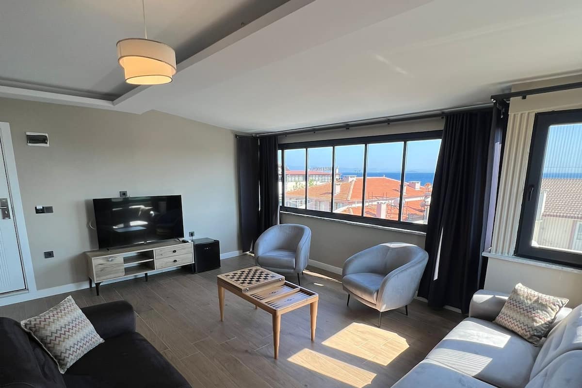 Una sala de estar moderna con un sofá, sillones, una mesa de centro y un televisor.