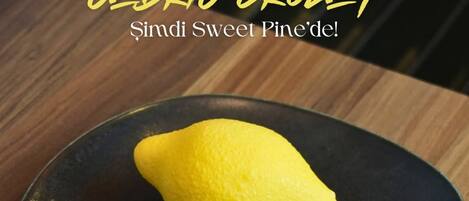 A lemon on a black plate on a wooden table.