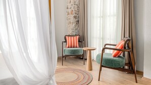 Ein Zimmer mit zwei Sesseln, einem kleinen runden Tisch und einem gewebten Teppich.