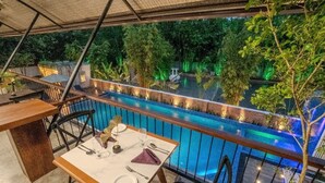 A dining area with a pool view, outdoor seating, and a covered section. - Grand Minaro  (Welipillawa)