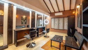 A modern salon with a reception desk, mirrored walls, and a seating area with two tables and chairs. - Grand Minaro  (Welipillawa)