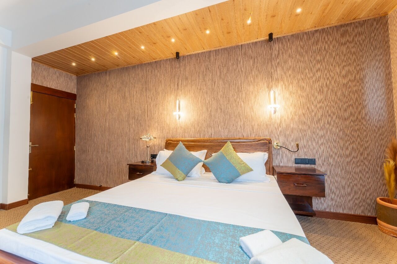 Ein Hotelzimmer mit einem großen Bett, einer Holzzieldecke und einer strukturierten Wand.