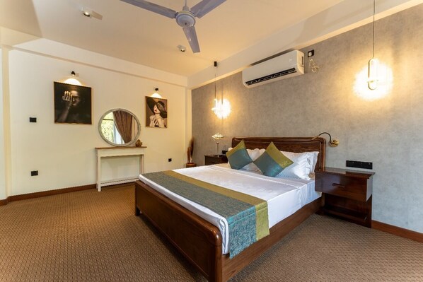 A bedroom with a wooden bed, a ceiling fan, an air conditioning unit, and wall-mounted lighting.