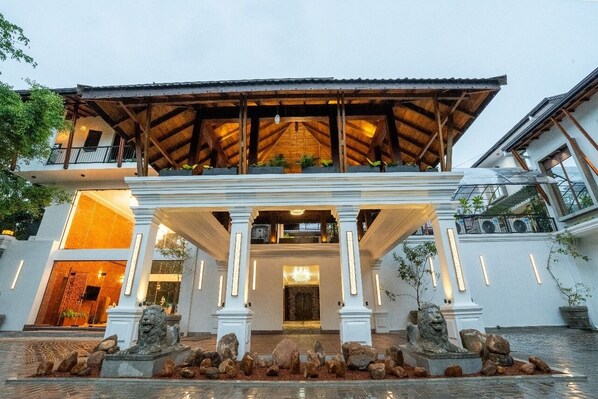 A building with a covered entrance, stone lion statues, and a well-lit interior.