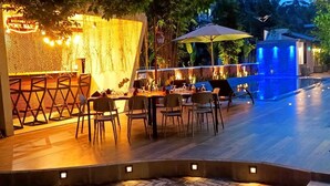 An outdoor dining area with tables and chairs, a pool with blue lighting, and a bar area with a sign that reads "Welcome to Fun Bar". - Grand Minaro  (Welipillawa)