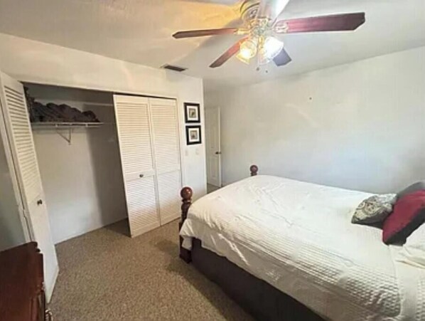 A bedroom with a bed, a ceiling fan, a closet, and a door. - Spacious 5-bedroom house in amazing Odessa, 1 acre, Lake Front (Odessa)