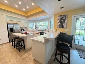 A modern kitchen with a central island, bar stools, and a large window providing natural light. - Spacious 5-bedroom house in amazing Odessa, 1 acre, Lake Front (Odessa)