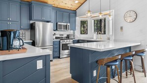Una cocina moderna con armarios azules, electrodomésticos de acero inoxidable y techo de madera.