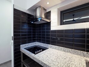 A modern kitchen with a built-in gas stove, black and white tiled backsplash, and a ceiling fan.