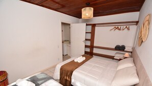 Une chambre d’hôtel avec deux lits, un plafond en bois, un luminaire suspendu et une armoire avec un miroir et des étagères.