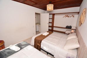 Ein Hotelzimmer mit zwei Betten, Holzboden, einer Pendelleuchte und einem Kleiderschrank mit Spiegel und Regalen.