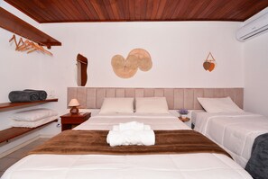 A hotel room with a wooden ceiling, a bed with a brown headboard, two bedside tables with lamps, and a wall decoration. - Apê a 150m da praia de Canasvieiras (Florianopolis)