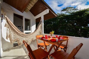 A wooden table set with red napkins, plates, and cups, a hammock, and a view of trees and sky.