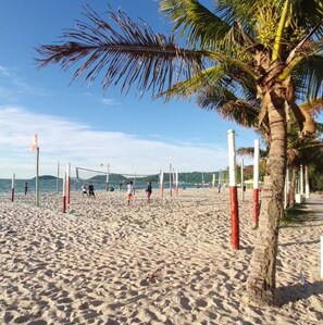 A beach volleyball court with palm trees and a clear sky. - Apê a 150m da praia de Canasvieiras (Florianopolis)