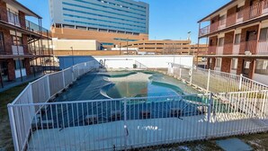Une piscine entourée d’une clôture blanche, avec un grand bâtiment en arrière-plan.