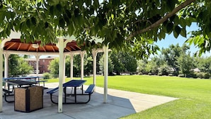 Un belvédère agrémenté de tables de pique-nique et de bancs, entouré d’une pelouse bien entretenue et d’arbres.