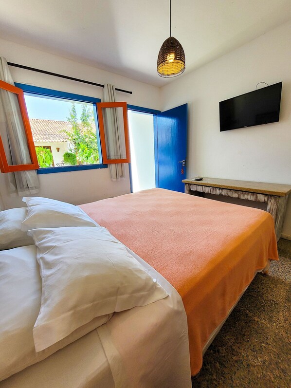 A bedroom with a bed, a television on the wall, and a window with curtains. - Pousada Nossa Casa Maracaipe (Ipojuca)