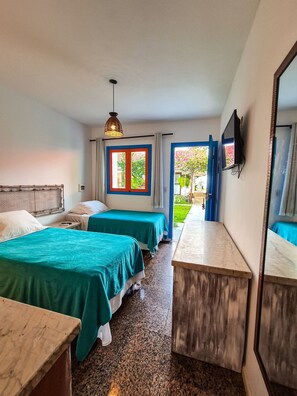 Habitación de hotel con dos camas, un escritorio, un televisor y vistas al exterior.