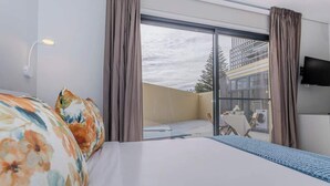 A hotel room with a large bed, a desk, a chair, a TV, and a balcony with a view of the city. - Casa do Senhor do Colégio (Ponta Delgada)