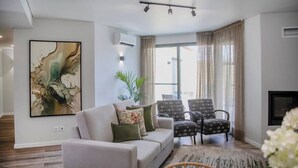 A modern living room with a sofa, two patterned chairs, a large abstract painting, and a fireplace. - Casa do Senhor do Colégio (Ponta Delgada)