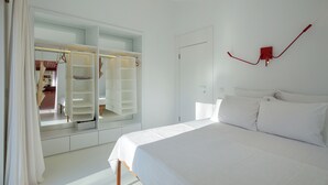 A bedroom with a large bed, a white wardrobe with open doors, and a red wall-mounted light fixture.