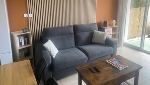 Una sala de estar moderna con un sofá gris, una mesa de centro de madera y una estantería.