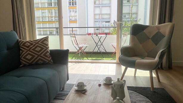 A living room with a sofa, armchair, and a coffee table set with teacups and a teapot. - Hyper center, 3 bedrooms, 3 bathrooms, Free parking, Beach 20 minutes away! (Saint-Nazaire)