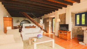 Un salón espacioso con un sofá blanco, una mesa de centro de madera y una chimenea de piedra.