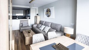A modern living room with a grey sofa, a wooden coffee table, and a dining table with placemats.