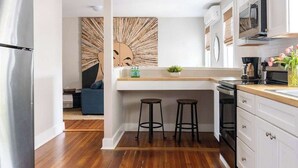 Una cocina moderna con una isla central, taburetes de bar y un refrigerador.