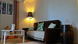 A living room with a sofa, a lamp, a table, and a decorative birdcage.