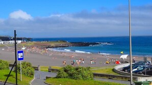 A beach with people, a road, and a streetlight.