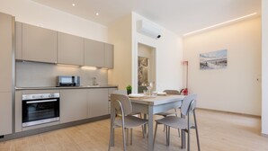A modern kitchen with built-in appliances, a dining table with chairs, and a painting on the wall. - Domus Mameli Apartment C (Cagliari)