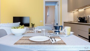 Een moderne keuken met een koffiezetapparaat, een fruitschaal en een eettafel gedekt voor twee personen.