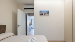 Een slaapkamer met een bed, een schilderij aan de muur en een open deur naar een badkamer.