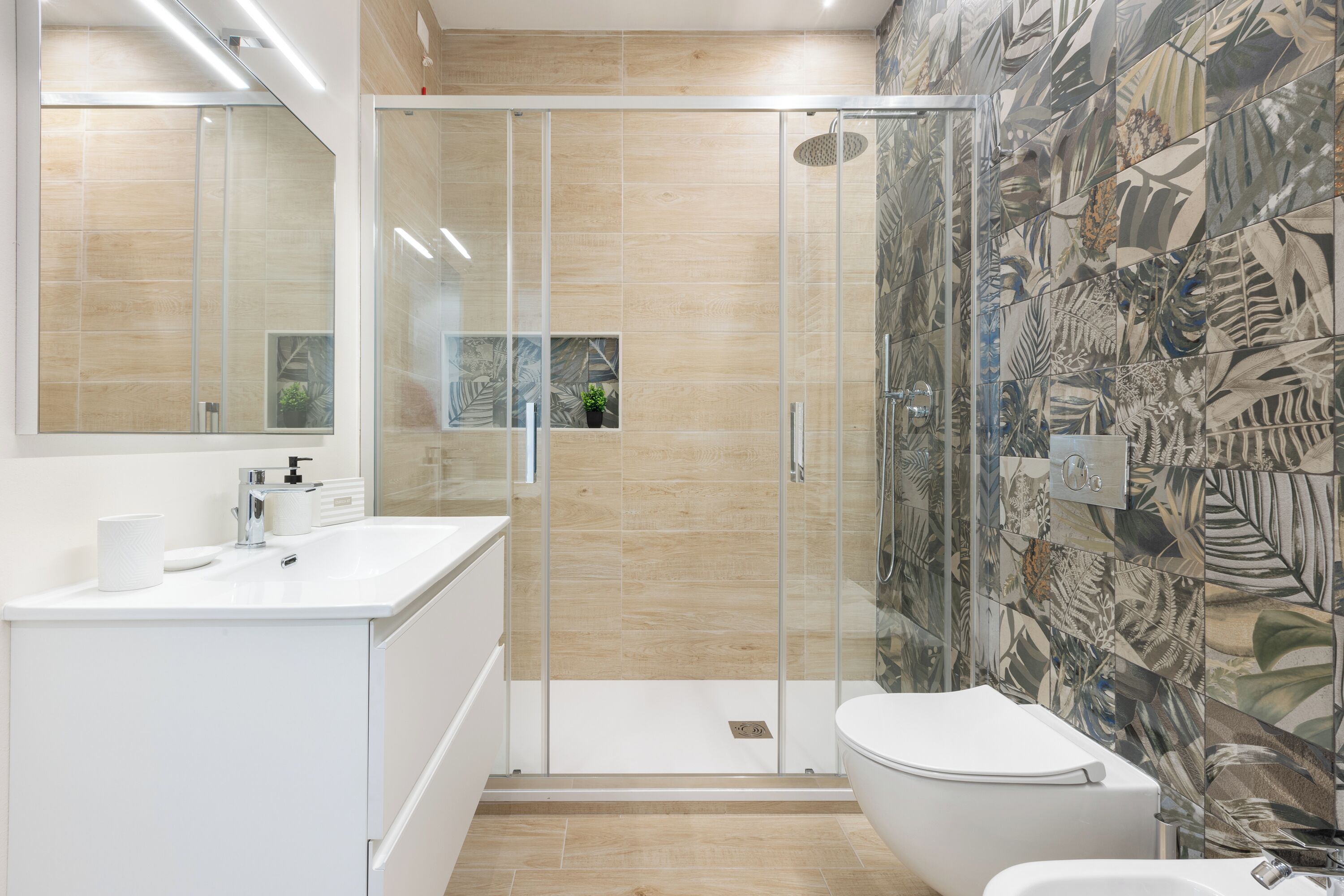 Een moderne badkamer met een douchecabine van glas, een wit wastafelmeubel en een toilet.