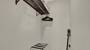 Une pièce équipée d’un étendoir fixé au plafond, d’un aspirateur et d’une étagère murale.