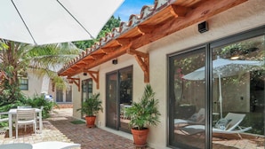 Un espace patio aménagé avec des meubles d’extérieur, des plantes en pot et une structure en forme de pergola.