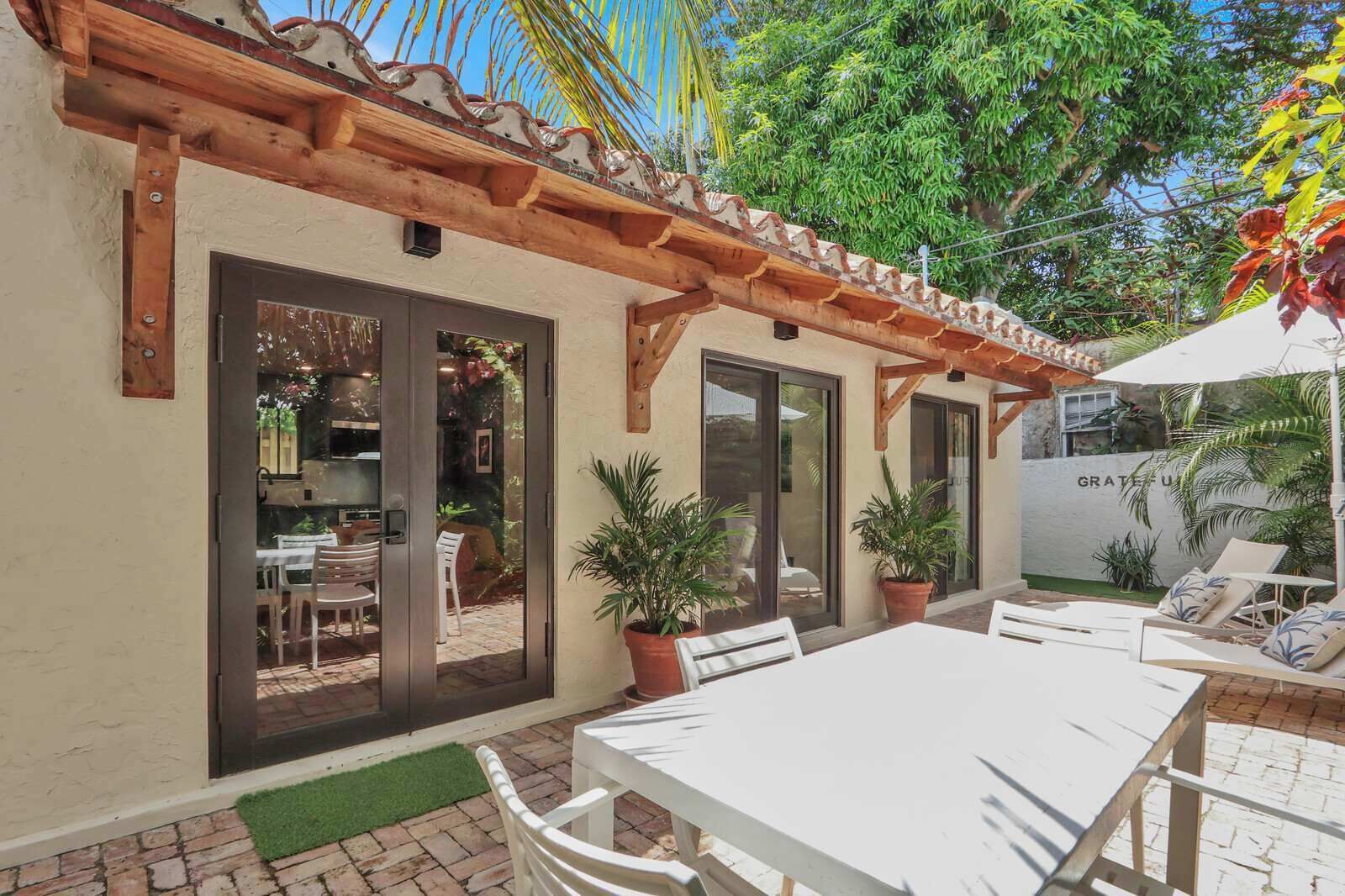 An outdoor patio with a table and chairs, a pergola, and potted plants.