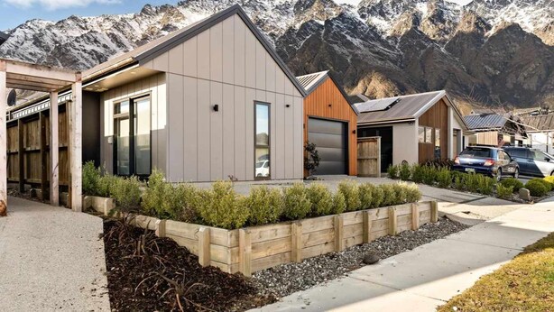 A modern residential building with a garage, a covered outdoor area, and a mountain backdrop. - Sunny Home Minutes to Remarkables Ski Field (Queenstown)