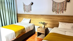 A hotel room with a wooden headboard, a bed with a yellow throw, a bedside table with a vase, and a nightstand. - Hotel Litan Machu Picchu (Aguas Calientes)