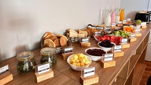 En buffet med forskellige retter og mærkater, blandt andet brød, frugt og tilbehør.