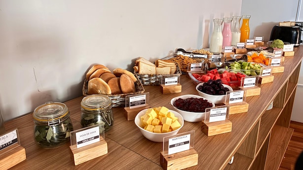 A buffet with various food items and labels, including bread, fruits, and condiments. - Hotel Litan Machu Picchu (Aguas Calientes)