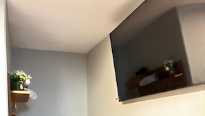 A small, neatly organized bathroom with a wooden vanity, a towel rack, a shelf with toiletries, and a mirror. - Hotel Litan Machu Picchu (Aguas Calientes)