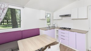 Una cocina compacta con estufa integrada, ventana con vista a árboles y un banco morado.