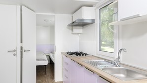 A compact kitchen with a window, a stove, and a sink. - Camping 2000 - Stacaravan Fiji (Osecná)