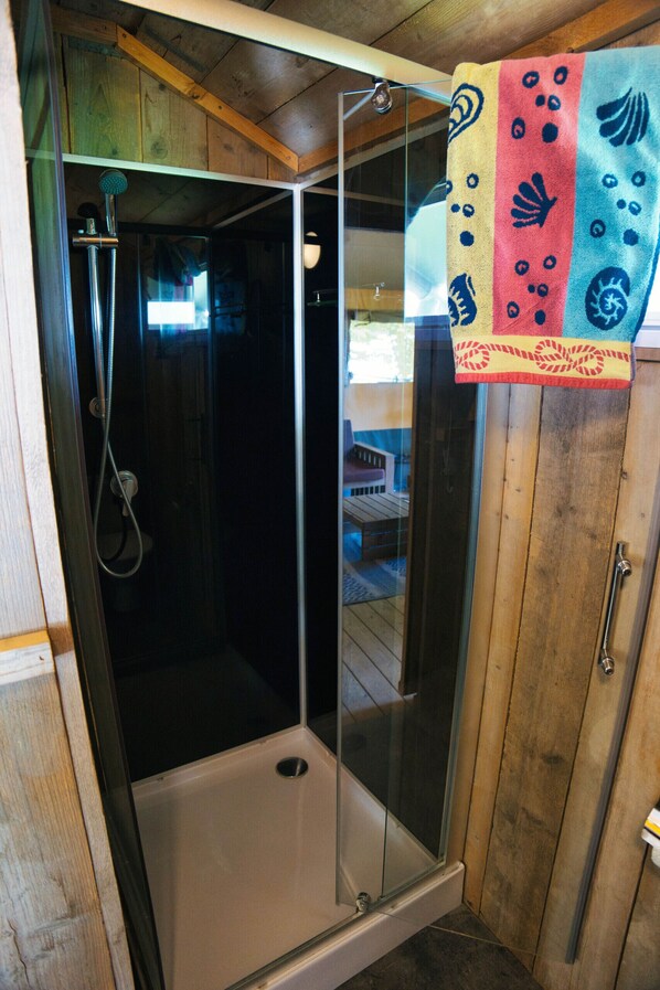 A glass-enclosed shower stall with a wooden interior and a towel hanging on the door.